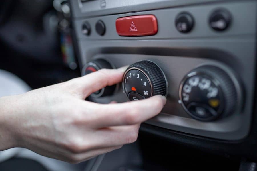 person turning on the air conditioning of his vehicle
